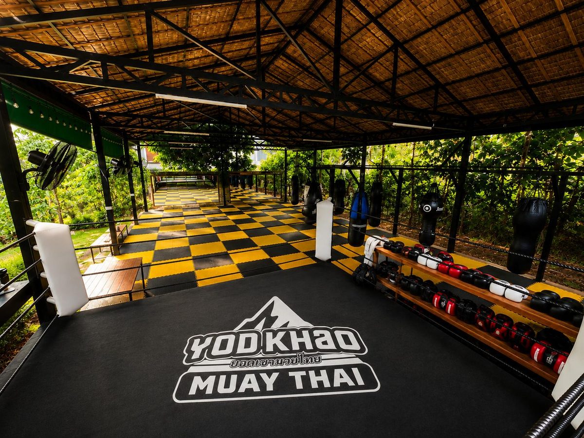 Training area with the Yod Khao logo on the mat and gloves on the rack